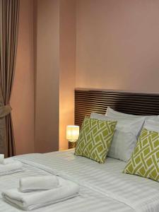 a bedroom with a bed with pillows and a lamp at Comfy family room hatyai in Ban Khlong Pleo