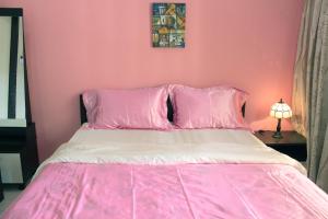 a pink bedroom with a bed with pink sheets and pillows at Memory Homestay in Kampong Baharu