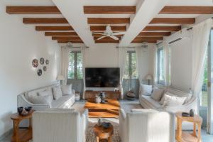 a living room with white furniture and a flat screen tv at Villa Mandarina by The Blue Kite - 4BHK Standalone Luxuxy Villa in Assagao with Large Private Pool, Pool Table, Kids Play Area, Garden, Caretaker & Security in Siolim