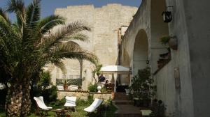 a building with chairs and a palm tree in front of it at Il Giardino di Eleonora in Matera