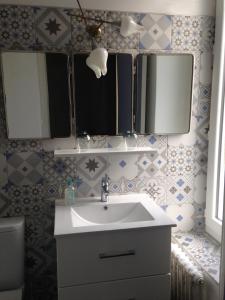 a bathroom with a sink and two mirrors and a toilet at La Maison Bleue in Rezé