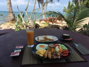 a table with a plate of breakfast food and a glass of orange juice at On the Beach Bungalows in Ban Nua