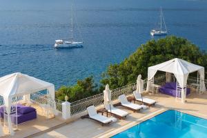 a swimming pool with chairs and a boat in the water at Lukka Exclusive Hotel – Adult Only +12 in Kaş