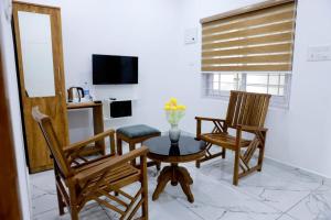 a living room with a table and chairs and a tv at AMAN Residency in Kallar Vattiyar