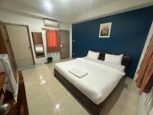 Un dormitorio con una cama grande con una pared azul. en Wellington Apartment, en Ban Nong Waeng