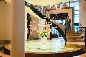 a woman walking down a spiral staircase with a vase of flowers at Hotel Nikko Kanazawa in Kanazawa
