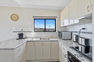 eine weiße Küche mit Spüle und Fenster in der Unterkunft See-Sea House - Sellicks Beach - C21 SouthCoast Holidays in Sellicks Beach