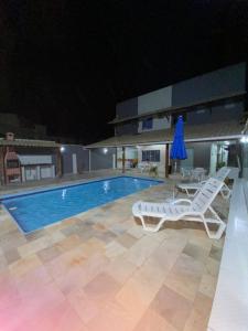 a pool at night with two lounge chairs and a umbrella at Suítes da lagoa monte alto in Arraial do Cabo