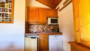 eine kleine Küche mit Holzschränken und einem weißen Geschirrspüler in der Unterkunft Appartement Proche Des Pistes in Saint-Gervais-les-Bains + 6 Fotos