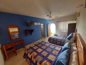 a bedroom with two beds and a couch and a mirror at Hotel Kootznoowoo in Puerto Escondido