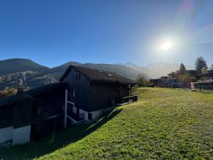 ein Haus auf einem grasbewachsenen Hügel mit der Sonne dahinter in der Unterkunft Appartement Proche Des Pistes in Saint-Gervais-les-Bains