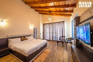 a bedroom with a large bed and a flat screen tv at StayVista at Sunset Springs with Heated Swimming Pool in Nainital