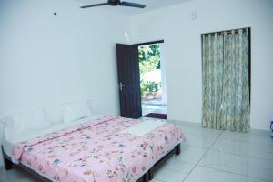 a bedroom with a bed with a pink comforter at Marari Arattukulam Villa in Mararikulam