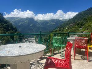 a table and chairs on a balcony with a view of mountains at L'Ashrum Cafe & Inn in Tosh