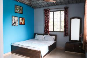a bedroom with a bed with blue walls and a window at Malama Stay Nisarg Villa 3BHK Karjat in Karjat