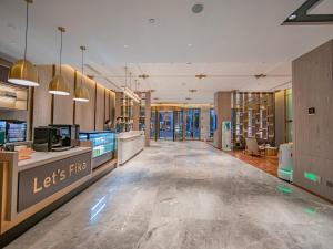 襄陽市にあるXiangyang Station Minfa World City Yishang Plus Hotelの廊下の長い店舗のロビー