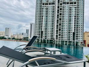 Una piscina con sillas y una mesa y un edificio. en Home Away From Home in Penang, en Jelutong