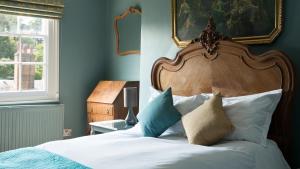 a bedroom with a bed with a wooden headboard and pillows at The Tunbridge Wells Hotel in Royal Tunbridge Wells