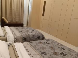 2 camas individuales en una habitación con silla en dotMy Homestay Kluang 15 pax - NETFLIX - WiFi - Autogate - 4 Rooms - 4 Bathrooms, en Keluang