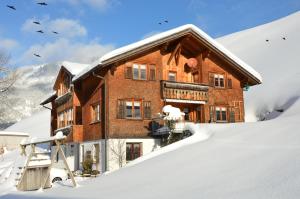 een groot bakstenen huis in de sneeuw bij Appartments Haus Monika in Schoppernau