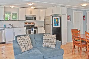 sala de estar con sofá azul y cocina en Ten Pines Cottage, en Ocean Shores