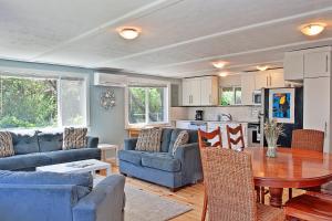 una sala de estar con sofás azules y una mesa de madera. en Ten Pines Cottage, en Ocean Shores