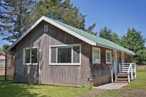 ein kleines Holzhaus mit grünem Dach in der Unterkunft Ten Pines Cottage in Ocean Shores