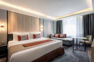 a hotel room with a large bed and a couch at Grace Hotel in Bangkok