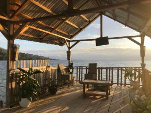 a wooden deck with chairs and a bench on the water at Dodoha Mosintuwu in Ratodena