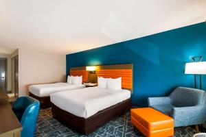 a hotel room with two beds and a chair at Comfort Inn Falls Church - Tysons Corner in Falls Church