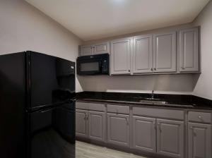 a kitchen with white cabinets and a black refrigerator at Comfort Inn Falls Church - Tysons Corner in Falls Church