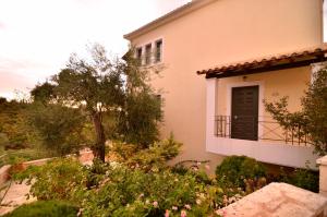 a house with a balcony and a tree at Niriides Luxury Apartments in Syvota