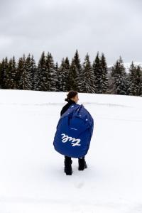 a person standing in the snow with a blue bag at Wild House Donovaly in Donovaly