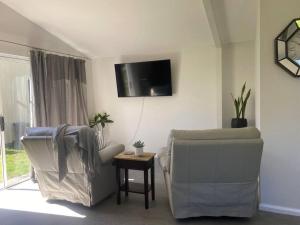 ein Wohnzimmer mit zwei Stühlen und einem Fernseher in der Unterkunft Rosehill cottage and bush retreat in Glastonbury