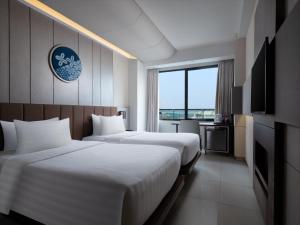 ein Hotelzimmer mit zwei Betten und einem Fernseher in der Unterkunft Santika Premiere Bintaro in Serpong