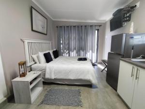 a bedroom with a white bed and a refrigerator at Anreith Close in West Point