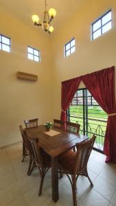 ein Esszimmer mit einem Holztisch und Stühlen in der Unterkunft Lunar Villa A'Famosa Resort by Holiday Pool Villa in Kampong Ulu Pegoh