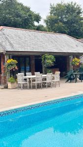 Una casa con una mesa y sillas al lado de una piscina. en Malston Mill Farm, en Kingsbridge