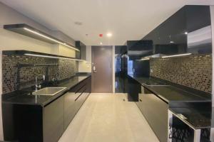 a large kitchen with black counters and a sink at Spacious Combined Studio Apartment at Warhol (W/R) Residence By Travelio in Semarang