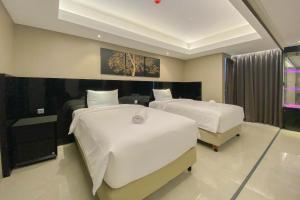 a bedroom with two beds with white sheets at Spacious Combined Studio Apartment at Warhol (W/R) Residence By Travelio in Semarang +18 photos