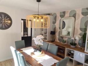 comedor con mesa con sillas y reloj en Les Epinettes chambres d'hôtes, en Crèvecoeur-le-Grand