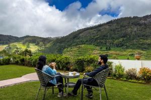 two people sitting at a table in chairs with a mountain at Away From Home - 2 - Rooms In Ooty, Home Stay Ooty in Ooty