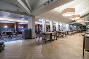 une salle à manger avec des tables et des chaises dans un restaurant dans l'établissement Mercure Palanga Vanagupe Resort & SPA, à Palanga