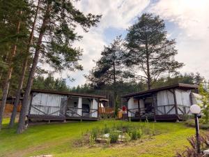 a couple of cottages in a field with trees at Къмпинг Alino Lake in Alino