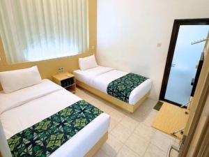 a hotel room with two beds and a window at El Rio Alun-Alun Tegal Hotel by Sajiwa in Tegal +4 photos