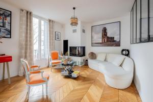 sala de estar con sofá blanco y sillas de color naranja en Veeve - Seagull’s House, en Boulogne-Billancourt