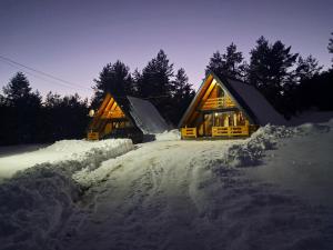 a log cabin in the snow at night at ROMANIJA vikendice in Koprivice