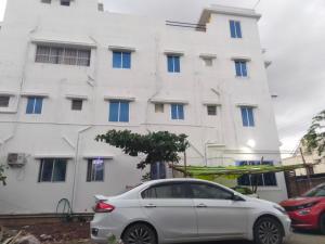 a white building with a car parked in front of it at Sri Vasishta Homestays in Theni