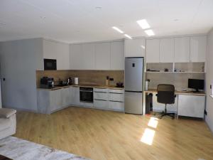 a kitchen with white cabinets and a desk and a chair at Centro Residence in Kluczbork +24 photos