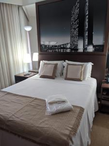 a hotel room with a large white bed with a bag on it at Hotel Bonaparte Moderno e versátil in Brasilia